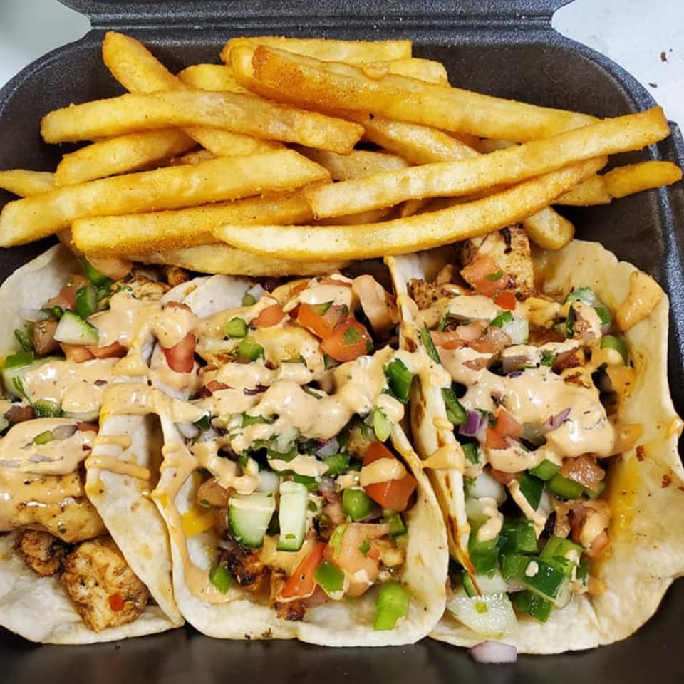 Three chicken tacos with pico de gallo and sauce, served with a side of golden french fries.